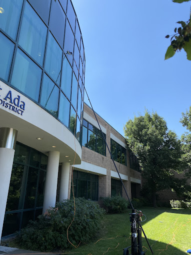 Modern glass and white building with Ada logo, surrounded by green trees